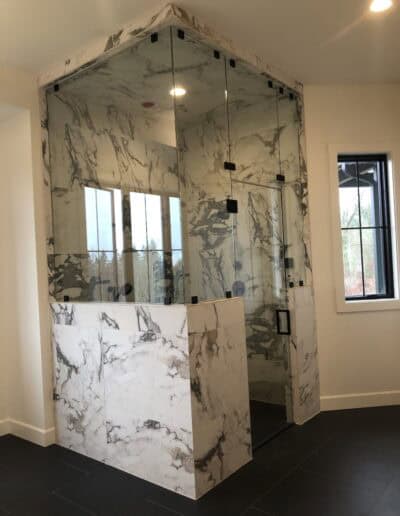 Clear glass steam shower with multiple panels and matte black square hardware